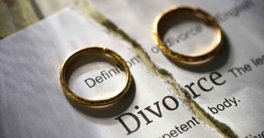A pair of wedding rings on a ripped piece of paper that reads "divorce"