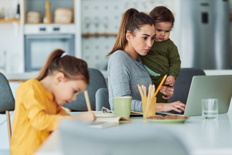 mother working at home surrounded by her children